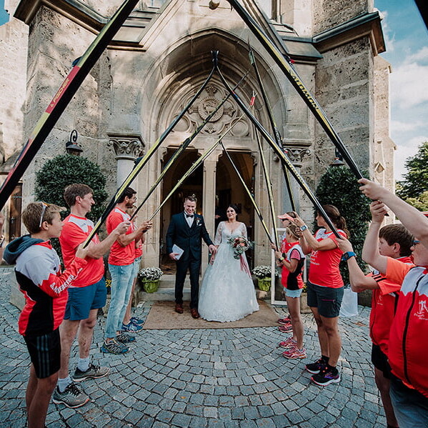 Hochzeitsfotograf_Zeremonie_Brautpaar_Ausgang_aus_der_Kirche_Gaeste_stehen_Skispalier